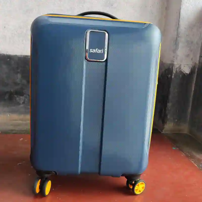 A 65cm medium trolley bag packed for a week-long trip, placed near a car boot before departure